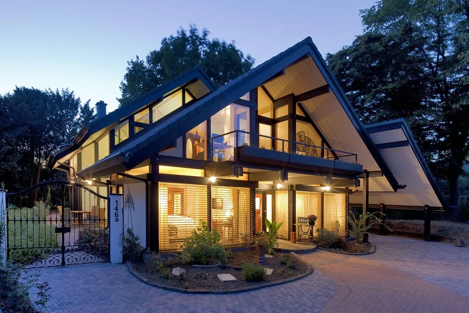 Modern timber-frame house with large windows lit at dusk